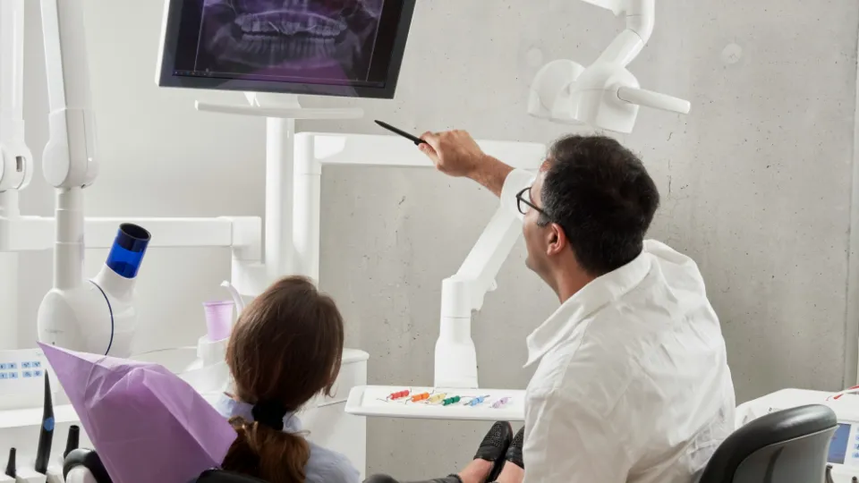 A dentist showing a patient her X-ray on a screen